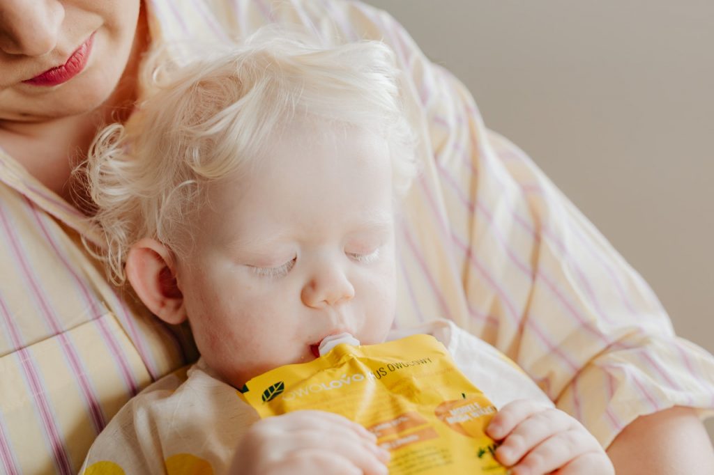 mom giving a toddler honey